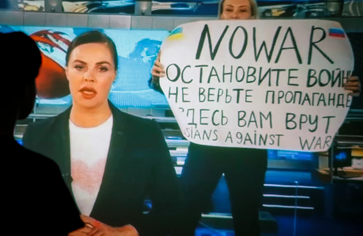 Женщина смотрит запись вечернего выпуска новостей Первого канала, в котором Марина Овсянникова появилась с написанным от руки антивоенным плакатом, Москва, Россия, 15 марта 2022 года. Фото: EPA / DSK