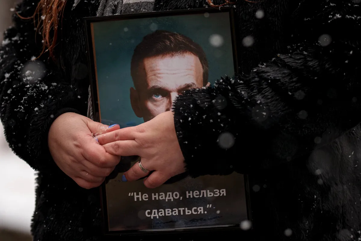 Пришедшая к импровизированному мемориалу в память об Алексее Навальном держит его фотографию у посольства России в Бухаресте, 16 февраля 2025 года. Фото: Andreea Alexandru / AP Photo / Scanpix / LETA