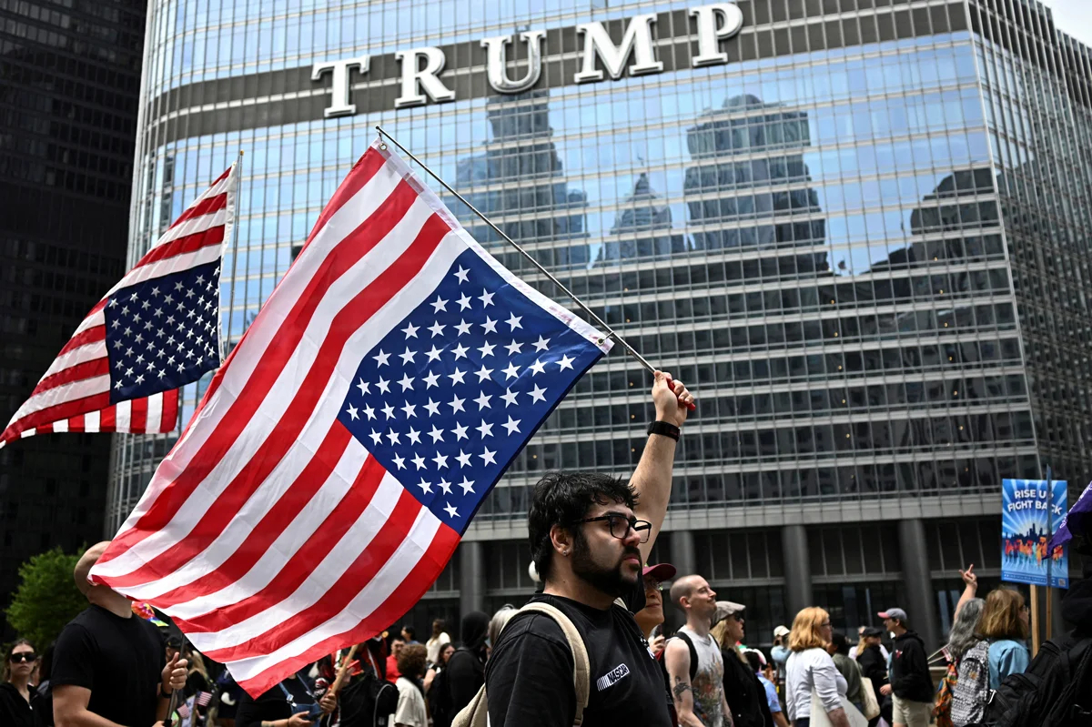 Участники шествия несут перевернутые флаги США перед отелем Trump International в Чикаго, Иллинойс, 14 июня 2025 года. Фото: Dylan Martinez / Reuters / Scanpix / LETA