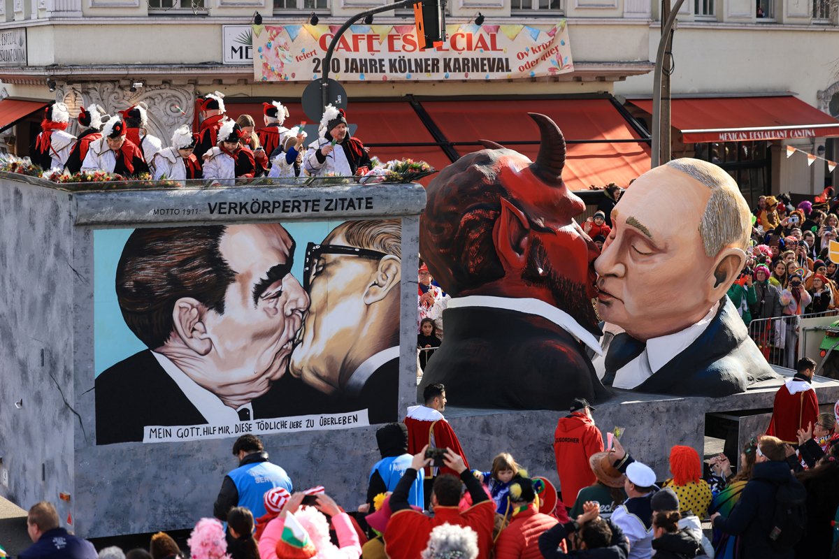 Карнавальная платформа с фигурой, изображающей поцелуй Путина с дьяволом, рядом с изображением поцелуя Леонида Брежнева и Эриха Хонеккера на Берлинской стене во время парада в Кёльне, 20 февраля 2023 года. Фото: Oliver Berg / dpa / Vida Press