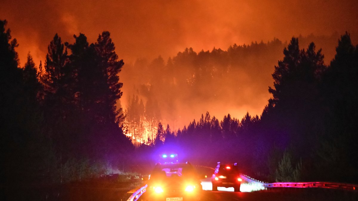 Машины едут по дороге на фоне горящего леса в районе Атамановки, Забайкальский край, 23 июня 2025 года. Фото: AP Photo / Scanpix / LETA