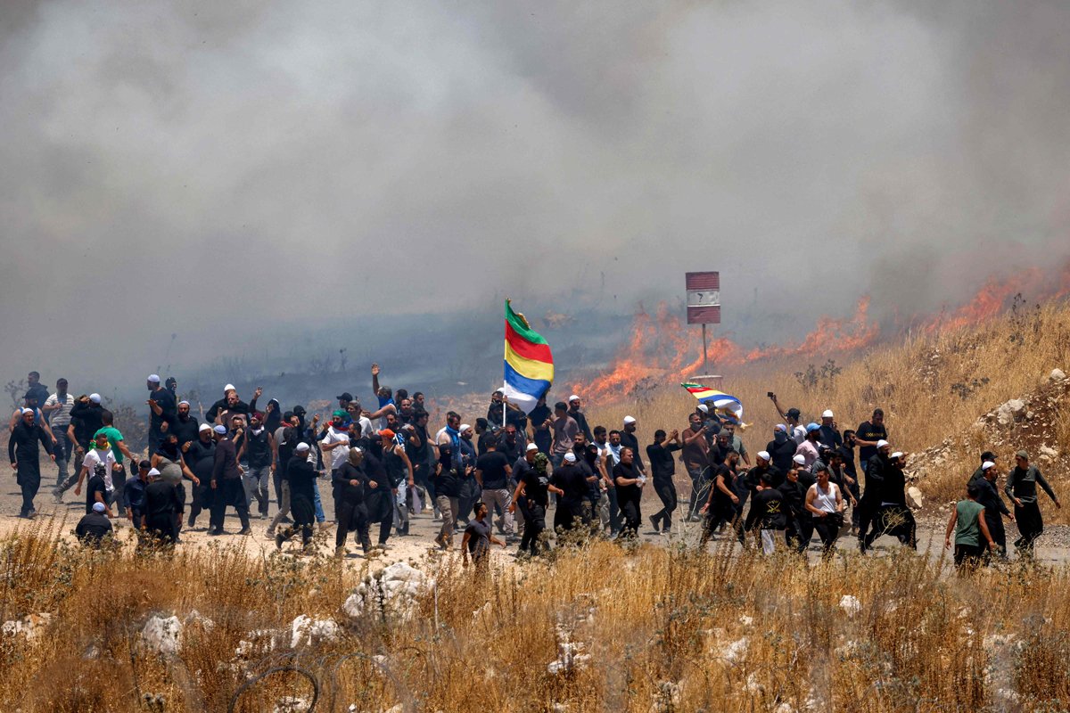 Члены друзской общины Сирии проходят через облако слезоточивого газа, выпущенного израильскими силами для их разгона на границе с аннексированными Голанскими высотами, 16 июля 2025 года. Фото: Jalaa Marey / AFP / Scanpix / LETA