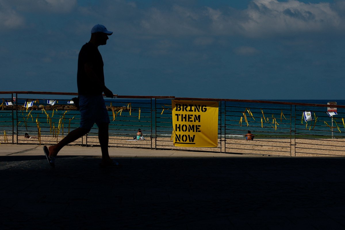 Прохожий на фоне плаката с надписью «Верните их домой сейчас» в поддержку заложников, захваченных во время нападения 7 октября, Тель-Авив, Израиль, 9 октября 2024 года. Фото: Gonzalo Fuentes / Reuters / Scanpix / LETA